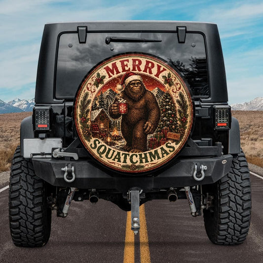 A circular decorative tire cover mounted on the spare tire well of a black Jeep Wrangler, featuring a Christmas-themed illustration of Bigfoot holding a mug with 'MERRY' above and 'SQUATCHMAS' below, set against a road and mountain background.